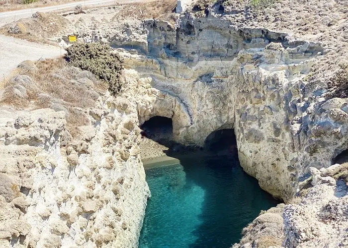 Papafragas em Milos: Em cima à esquerda o sinal de alerta e por baixo os degraus que levam à praia com as grutas.