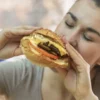 Mulher comendo sanduíche.