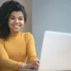 Mulher no laptop sorrindo.