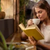 Mulher lendo livros e tomando café.