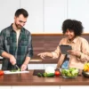 Casal na cozinha com tablet na mão.