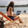 Mulher com computador na praia.