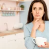 Mulher pensativa na cozinha.