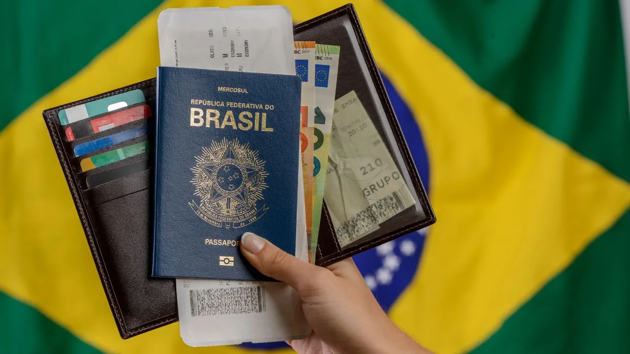 Passaporte brasileiro e bandeira ao fundo.